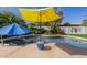 Serene pool area with colorful umbrellas and a glass table, surrounded by lush landscaping at 24416 S Lakestar Dr, Sun Lakes, AZ 85248