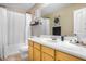 A bright bathroom features a shower-tub combo with a white shower curtain and a wooden vanity with ample counter space at 29983 W Fairmount Ave, Buckeye, AZ 85396