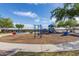 Full playground with swings, slides, and spring riders, surrounded by trees and a paved walkway on a sunny day at 29983 W Fairmount Ave, Buckeye, AZ 85396