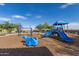 Bright blue playground equipment including slides, a hippo rocker, and swings, set against a clear blue sky with scattered clouds at 29983 W Fairmount Ave, Buckeye, AZ 85396