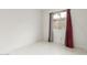 An empty bedroom with red curtains, white tile flooring, and white walls at 3042 N 87Th Ave, Phoenix, AZ 85037