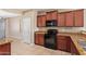 Well-equipped kitchen featuring dark wood cabinetry, granite countertops, and black appliances at 41375 W Barcelona Dr, Maricopa, AZ 85138