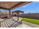 Covered patio with outdoor kitchen, pergola, and desert landscaping with putting green at 4658 S Rufino Ln, Gold Canyon, AZ 85118