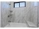 Elegant bathroom featuring marble-patterned tile, built-in shelves, and a comfortable bathtub at 5468 E Dove Valley Rd, Cave Creek, AZ 85331