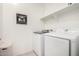 Bright laundry room with front load washer and dryer, storage shelf, and decorative wall art at 5624 S Winchester --, Mesa, AZ 85212