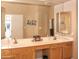 Bathroom with double sinks, wood cabinets, vanity, a large mirror, and a door leading to a walk-in closet at 5705 S Pinnacle Ln, Gold Canyon, AZ 85118