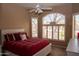 Bright bedroom with a bed dressed in a red and white comforter set, ceiling fan, and large window at 5705 S Pinnacle Ln, Gold Canyon, AZ 85118