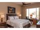 Bedroom with a large window overlooking the backyard, a dark wooden bed frame, and a decorative ceiling fan at 5705 S Pinnacle Ln, Gold Canyon, AZ 85118