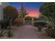 Inviting front entrance with illuminated lamps, decorative iron gate, and lush desert landscaping at sunset at 5914 E Dale Ln, Cave Creek, AZ 85331