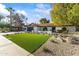 A stylish home with an expansive green lawn, xeriscaping, dark garage, and appealing curb appeal at 7607 E Charter Oak Rd, Scottsdale, AZ 85260