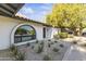 A close up of the xeriscaped front yard and unique, arched windows of this lovely home at 7607 E Charter Oak Rd, Scottsdale, AZ 85260