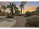 Expansive backyard with palm trees, gravel landscaping, and privacy wall at sunset at 9513 E Hercules Dr, Sun Lakes, AZ 85248