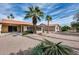 Backyard showing desert landscaping, palm trees, enclosed patio, and a covered patio at 9513 E Hercules Dr, Sun Lakes, AZ 85248