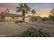 Backyard showing desert landscaping, palm trees, enclosed patio, and a covered patio at sunset at 9513 E Hercules Dr, Sun Lakes, AZ 85248