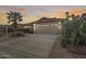 Front exterior view of the home featuring a two-car garage and mature desert landscaping at 9513 E Hercules Dr, Sun Lakes, AZ 85248