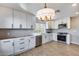 Bright kitchen with white cabinetry, stainless steel appliances, a modern light fixture, and wood-look flooring at 9513 E Hercules Dr, Sun Lakes, AZ 85248