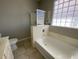 Bathroom featuring a tub with shower, glass block window, and neutral tile at 10030 W Illini St, Tolleson, AZ 85353