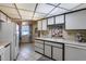 Bright kitchen featuring white cabinets, tiled flooring, and a window with patterned curtains at 17428 N Boswell Blvd, Sun City, AZ 85373