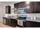 Close up of kitchen featuring stainless steel appliances, granite countertops, and dark cabinets at 17580 W Country Club Ter, Surprise, AZ 85387