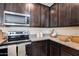 Close up of the kitchen featuring granite countertops, dark cabinets, and stainless steel appliances at 17580 W Country Club Ter, Surprise, AZ 85387