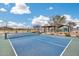 Well-maintained blue and green community tennis court with shaded benches under a bright blue sky at 17580 W Country Club Ter, Surprise, AZ 85387