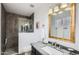 Modern bathroom featuring a sleek glass shower, dark stone shower walls and sink with a gold-framed mirror at 18624 N 92Nd Dr, Peoria, AZ 85382