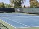 Well-maintained community tennis court with pristine blue surface and surrounding green fence for privacy at 18624 N 92Nd Dr, Peoria, AZ 85382