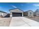 View of the home's driveway and two car garage, plus the low maintenance desert rock yard at 18743 N Avelino Dr, Maricopa, AZ 85138