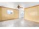 A bright and spacious living room featuring wood-paneled walls, a ceiling fan, and abundant natural light at 200 E Rose Ln, Avondale, AZ 85323