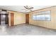 Large living room featuring wood-paneled walls, ceiling fan, and ample natural light at 200 E Rose Ln, Avondale, AZ 85323