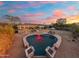 Aerial view of a heart-shaped pool with a desert sunset, covered patio, and an outdoor kitchen at 27606 N 61St Pl, Scottsdale, AZ 85266