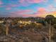 An aerial view of a beautiful backyard with desert landscaping and a stunning sunset at 27606 N 61St Pl, Scottsdale, AZ 85266