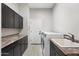 Functional laundry room with dark cabinetry and built in sink at 27606 N 61St Pl, Scottsdale, AZ 85266