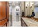 Elegant bathroom featuring a tile countertop, vanity and glass enclosed shower with stylish lighting fixtures at 27701 N Lucero Dr, Rio Verde, AZ 85263