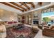 Cozy living room with stone fireplace, beamed ceiling, and comfortable seating area at 27701 N Lucero Dr, Rio Verde, AZ 85263