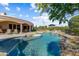 Resort-style pool with rock features, tanning island, lounge chairs and patio with covered seating at 27701 N Lucero Dr, Rio Verde, AZ 85263