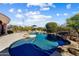 Inviting pool with rock features, lounge chairs, and umbrella, surrounded by desert landscaping at 27701 N Lucero Dr, Rio Verde, AZ 85263