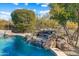 Close up of the rock waterfall feature of the beautiful pool surrounded by mature landscaping at 27701 N Lucero Dr, Rio Verde, AZ 85263