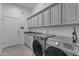 Laundry room featuring front loading washer/dryer, gray countertop, and white shaker cabinetry at 3459 E Mockingbird Dr, Gilbert, AZ 85234