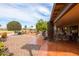 A spacious tiled back patio with seating area, overlooking a well-manicured garden and green space at 3648 N 162Nd Ave, Goodyear, AZ 85395