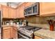 Close up of stainless steel stove and microwave, next to granite countertops, and wood cabinets at 3767 W Desert Creek Ln, Phoenix, AZ 85086