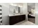 Bathroom featuring a double vanity with dark wood cabinets, a large mirror, and neutral finishes, providing a functional space at 41954 W Plata St, Maricopa, AZ 85138