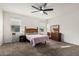 Bright bedroom with carpet, a ceiling fan, a wooden dresser, and a large window, creating a cozy retreat at 41954 W Plata St, Maricopa, AZ 85138