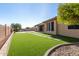 Expansive backyard featuring lush artificial grass, a paved patio, and a walkway of stone squares to the back patio at 42043 N Bradon Way, Phoenix, AZ 85086