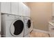 The laundry room features white appliances with white cabinets offering storage for household cleaning supplies at 42043 N Bradon Way, Phoenix, AZ 85086