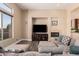 Cozy living room with a large sectional sofa, fireplace, and a sunlit view of the yard at 42043 N Bradon Way, Phoenix, AZ 85086