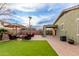 This backyard features artificial turf, a paver patio, and an outdoor seating area with umbrellas and a fire pit at 42577 W Rosalia Dr, Maricopa, AZ 85138