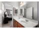 Bathroom featuring a dual sink vanity with wood cabinets, a large mirror, and ample lighting at 42577 W Rosalia Dr, Maricopa, AZ 85138