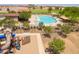 Aerial view of the community pool with lounge chairs, landscaping, and play area at 42577 W Rosalia Dr, Maricopa, AZ 85138