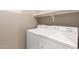 This laundry room showcases a white washer and dryer and includes a shelf above for storage at 42577 W Rosalia Dr, Maricopa, AZ 85138